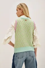 Chaleco de punto sin mangas con diseño de zigzag en tonos verde y beige. Presenta cuello redondo y bordes acanalados en contraste color menta y lila.