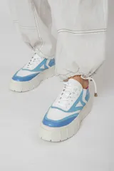 Zapatillas deportivas de cuero color beige, blanco y marrón, con cordones y suela de goma.