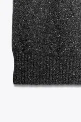 Top de punto jaspeado en color gris oscuro, con cuello alto y diseño halter sin mangas. Confeccionado con una mezcla que incluye lana, presenta terminaciones acanaladas en el cuello y el ruedo.