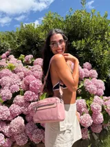 Bandolera de diseño moderno y funcional, confeccionada en nylon color marrón claro. Cuenta con múltiples compartimentos con cierre metálico, herrajes plateados y una correa ancha ajustable con detalle de marca.