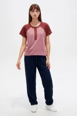 Remera de manga corta con diseño color block en tonos rosado y marrón, con escote en V y cartera con botones frontales.