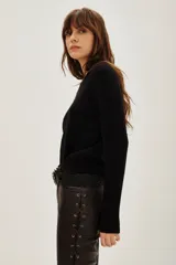 Sweater de punto color negro, con cuello redondo y mangas largas con puños acanalados.