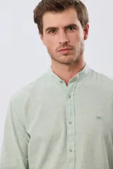 Camisa de lino y algodón color beige, de manga larga, con cuello mao y cierre frontal con botones. Presenta un pequeño bordado al tono en el pecho.