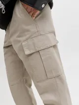 Pantalón cargo de corte relajado y tiro medio color beige, confeccionado en tejido de sarga con bolsillos laterales y traseros.