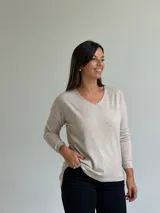 Sweater de punto fino en color beige, con escote en V y mangas largas con puños ajustados.