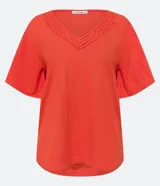 Blusa de manga corta color naranja, confeccionada en tejido Orly, con escote en V con detalle de costuras trabajadas.