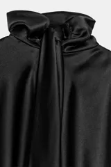 Vestido corto de tejido satinado en color negro, con cuello subido tipo foulard, manga larga amplia y detalle de frunces en la cintura.