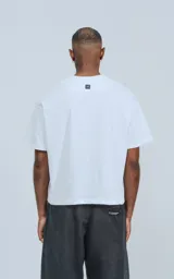 Remera de corte boxy con silueta amplia y recta, confeccionada en algodón premium. Presenta cuello redondo y mangas cortas con un calce relajado.