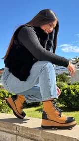 Borcegos de cuero tostado con plataforma bicolor, puntera y talón negros, detalles en animal print y cordones oscuros.