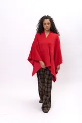 Ruana de tejido de punto color rojo, con diseño envolvente y bordes decorados con costuras a contraste en tono fucsia.