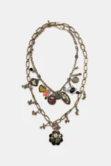 Pack de dos collares de eslabones metálicos labrados en tono dorado envejecido. El collar más largo presenta un dije colgante principal con forma de flor negra y detalles dorados, además de pequeños dijes colgantes. El collar más corto tiene múltiples dijes colgantes que incluyen un corazón amarillo, una piedra rosada, un dije ovalado negro con flores doradas, un dije redondo con flor roja, un dije cuadrado con mariposa negra, y otros dijes pequeños como una perla y un dije negro ovalado.