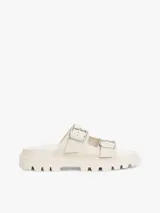 Sandalias planas de color blanco hueso con dos tiras ajustables mediante hebillas metálicas. Cuentan con una suela gruesa y dentada de plataforma.