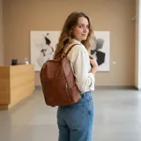 Mochila de cuero sintético marrón, amplia y resistente, con compartimento principal y bolsillos frontales y laterales con cierre.