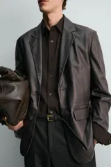 Blazer relaxed fit de cuero marrón oscuro, con cuello de solapa de muesca, cierre de un botón, bolsillos con solapa en la cadera y abertura central en la espalda.