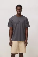 Remera de algodón color gris oscuro, con cuello redondo, mangas cortas y detalle de bordado pequeño en forma de cruz en el centro del pecho.
