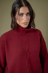 Buzo de cuello alto tejido en lana, con diseño de ochos en el centro y mangas largas con hombros caídos.