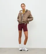 Campera puffer deportiva Get Over, color blanco con detalles de bies en color negro a lo largo de las mangas. Presenta cuello alto con capucha integrada, cierre frontal con botones a presión, bolsillos laterales con cremallera y puños con elásticos.