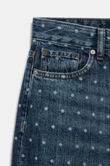Jeans de tiro medio con corte tapered y largo al tobillo. Presenta un diseño de cinco bolsillos, cierre frontal con cremallera y botón, y un estampado de lunares a contraste sobre un tejido denim con efecto lavado.