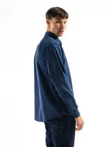 Camisa de manga larga color gris oscuro, confeccionada en algodón, con cuello clásico, cierre frontal con botones, bolsillo de parche en el pecho y corte clásico.