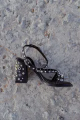 Sandalias negras con tiras finas adornadas con apliques metálicos y perlas. Taco de 9 cm y base cuadrada.