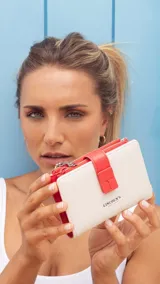 Billetera mediana de símil cuero bicolor, en tonos blanco marfil y coral, con cierre de presilla y compartimentos con cierre.
