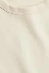 Remera color crema de punto de algodón tupido con cuello redondo ribeteado acanalado y mangas cortas.