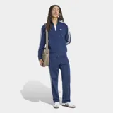 Campera deportiva Adidas Originals Firebird Drop Needle de color azul marino, con cierre frontal, cuello alto y bolsillos laterales. Presenta las clásicas tres tiras blancas en las mangas, el logotipo del Trifolio bordado en el pecho y un sutil patrón de rayas verticales en relieve.