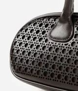 Cartera tipo bowling de Satinato en color negro, con estructura alargada, base redondeada y diseño geométrico calado. Cuenta con doble asa superior y cierre de cremallera metálica en tono dorado.