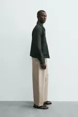 Cazadora relaxed fit color verde oscuro, confeccionada en tejido de algodón. Cuenta con cuello solapa, manga larga con puño abotonado, bolsillos plastrón con solapa en la cadera y cierre frontal de botonadura.