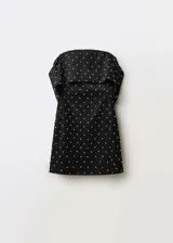 Vestido corto de fiesta en tejido satinado negro, con diseño entallado y escote palabra de honor con solapa vuelta. Presenta apliques decorativos brillantes distribuidos por toda la prenda y cierre de cremallera en la parte posterior.