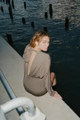 Vestido corto de manga larga con escote en pico, diseño con frunces en el cuerpo y detalle de lazada en el cuello.