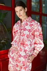 Camisa blanca con estampado de aves, edificios y motivos florales en color rojo.