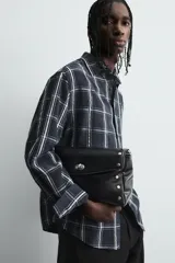 Camisa de corte relajado confeccionada en tejido fluido de cupro y viscosa, con estampado de cuadros, cuello solapa, manga larga con puño abotonado y cierre frontal de botones.