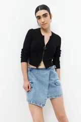 Minifalda de jean celeste con corte asimétrico, bolsillos de parche con solapa y tiras ajustables con hebillas en los laterales.