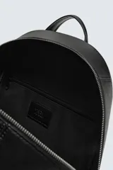 Mochila negra con textura grabada, compartimento principal con cierre de cremallera, bolsillo interior con cremallera, bolsillo frontal con cremallera, parte posterior acolchada con banda de sujeción para equipaje, asa de mano y dos asas de hombro ajustables.