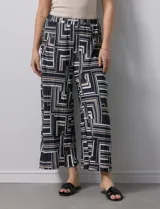 Pantalón ancho estilo palazzo, de seda fría plisada con estampado geométrico en negro, blanco y beige. Tiene pretina ancha elastizada y largo crop.