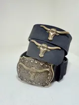 Cinto negro con hebilla y apliques metálicos con forma de cabeza de toro.