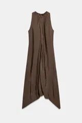 Vestido midi de color marrón con acabado satinado, cuello redondo con detalle fruncido y diseño sin mangas. Presenta un corte fluido con bajo asimétrico y bolsillos laterales ocultos.
