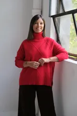 Polerón de punto color rojo con cuello alto y diseño de rombos texturizados. Presenta mangas largas con puños acanalados y un corte holgado con ruedo asimétrico.