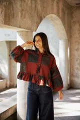 Kimono de lino con diseño patchwork en tonos rojizos y oscuros, con cuello camisero, cierre frontal de botones, mangas largas abullonadas y ruedo con volados.