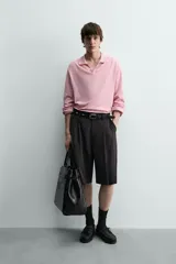 Polo de punto ligero color rosado, con cuello solapa, abertura frontal en V y manga larga.