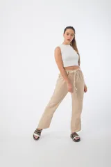 Pantalón de tela color beige, con cintura alta elastizada y cordón ajustable.