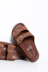 Sandalias de dos tiras en color camel con hebillas metálicas doradas y tachas decorativas, de suela plana y anatómica.