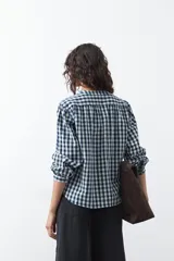 Camisa de algodón con estampado de cuadros vichy en tonos azul y blanco. Presenta escote en V con cierre frontal de botones, mangas largas con puños y un corte levemente holgado con frunces en hombros y espalda.