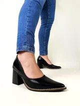 Zapatos de tacón cuadrado color negro, confeccionados en cuero, con punta fina y costuras decorativas visibles en el borde de la suela.