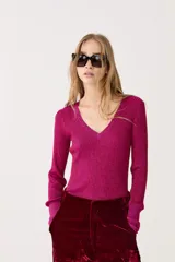 Top fucsia de lurex con escote en V, manga larga y tejido tipo rib.