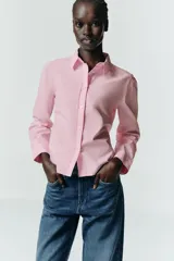 Camisa de corte clásico confeccionada en popelín de algodón, con cuello solapa, manga larga con puños y cierre frontal mediante botones.