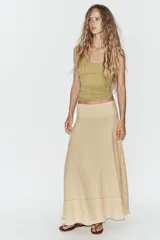 Falda larga de tiro medio en color beige, con tejido de textura cuadriculada. Presenta un diseño acampanado con detalle de costura horizontal y bajo acabado en volante. Cierre lateral con cremallera oculta.