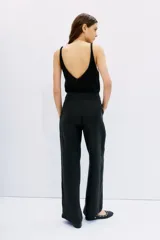 Pantalón palazzo negro de tiro alto, confeccionado en cupro y viscosa, con bolsillos diagonales laterales, bolsillos ojal falsos en la espalda y cierre lateral invisible.