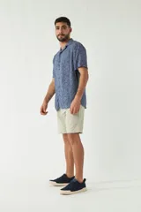 Camisa de manga corta con cuello cubano, confeccionada en viscosa con estampado de hojas en tonos azules. Presenta cierre frontal abotonado y corte slim.